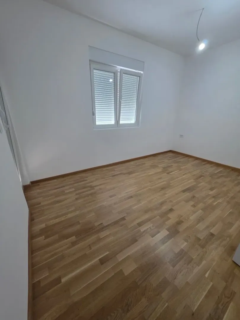 Prazna soba sa parketom i bijelim zidovima.