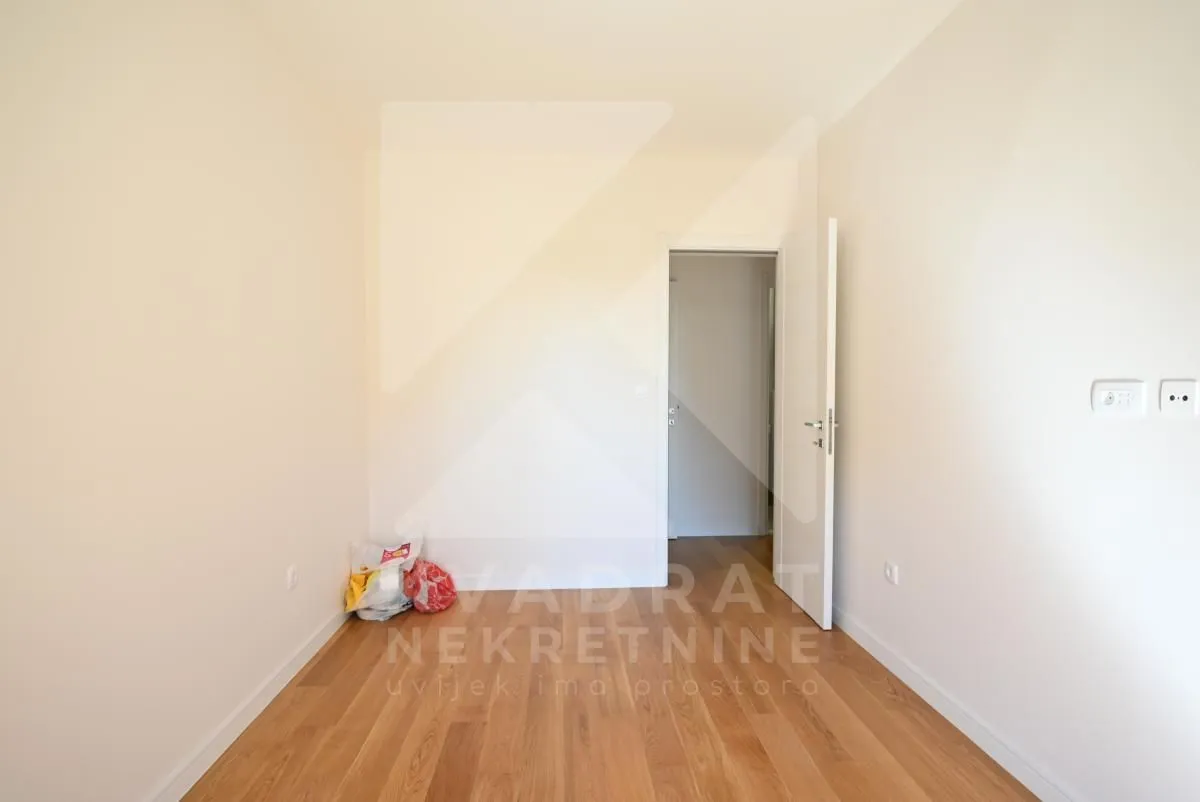 Empty room with light hardwood flooring and an open door.