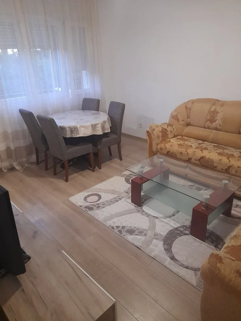 Dnevna soba sa garniturom za sjedenje i trpezarijskim stolom pored prozora.