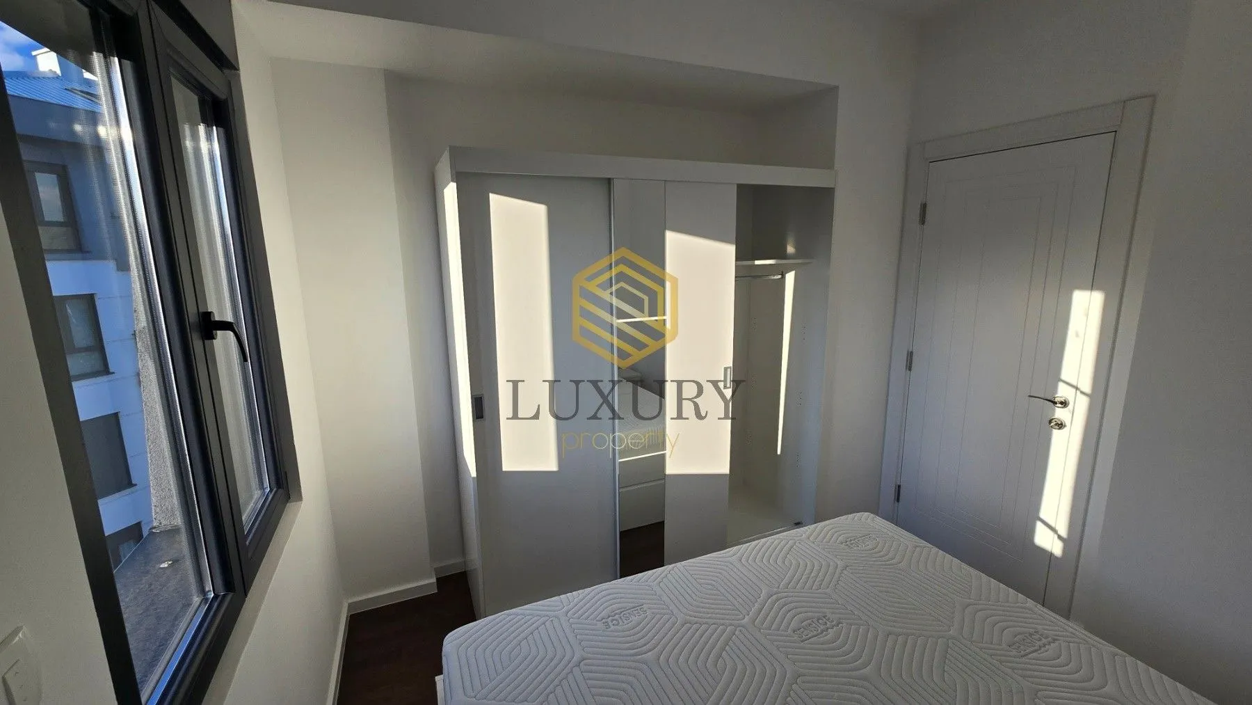 Bright bedroom with a white wardrobe and bed.