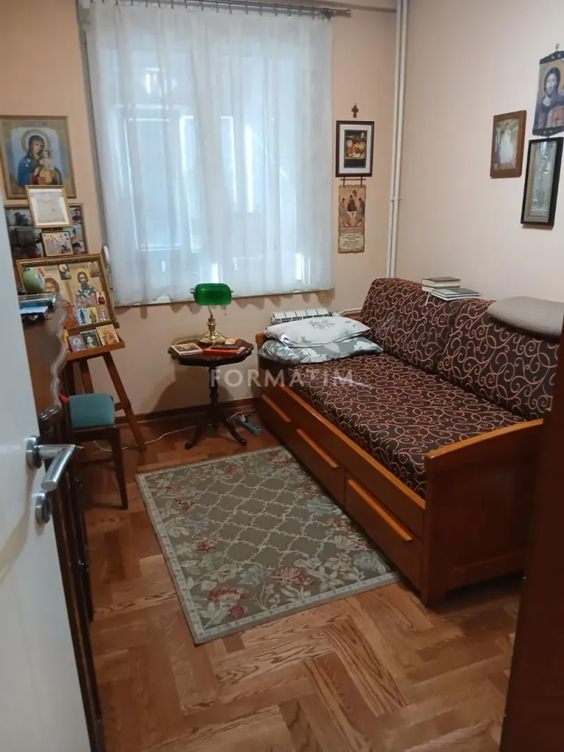 Manja soba sa kaučem, tepihom i ikonama na zidu.