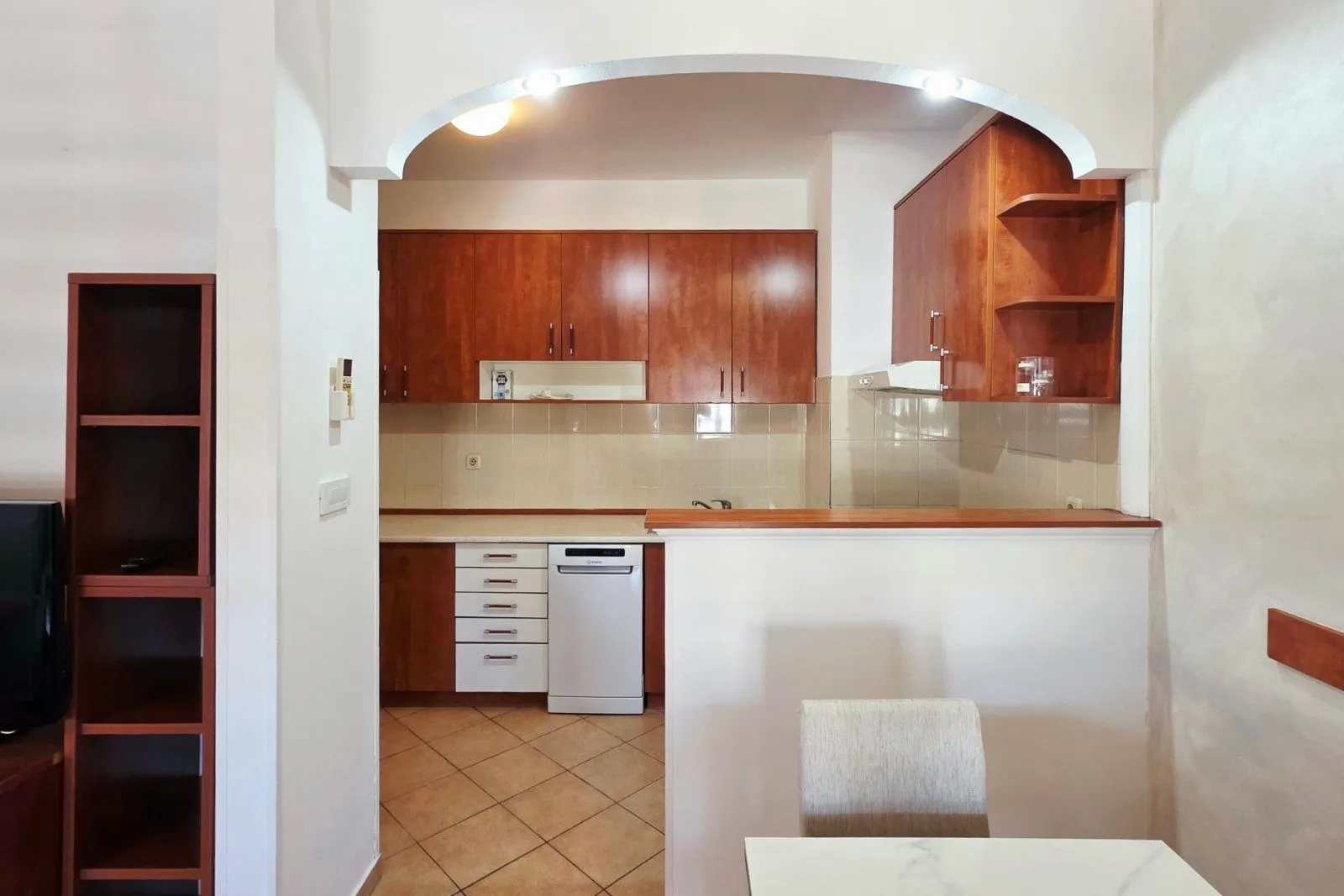 View of the kitchen with wooden cabinets and a white dishwasher.