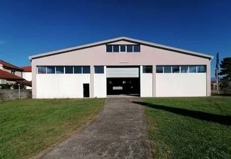 Exterior view of an industrial building with a lawn and access path.
