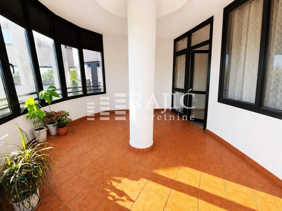 Spacious enclosed terrace with ceramic tile flooring and a central column.
