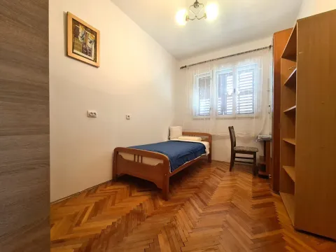 A simple bedroom with a single bed, wooden furniture, and parquet flooring. - image 7