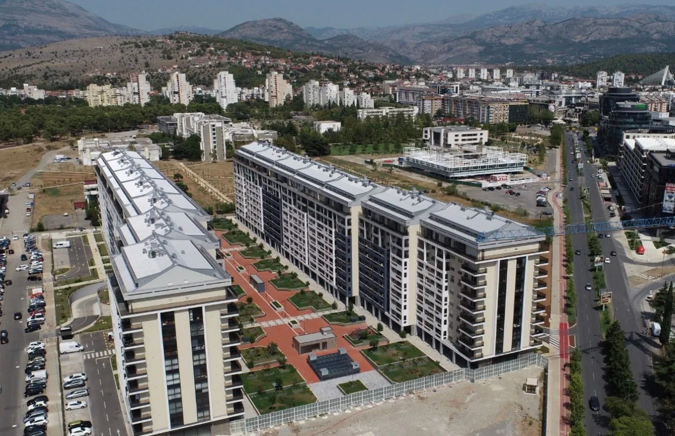 Pogled iz vazduha na stambeni kompleks sa uređenim dvorištem i okolnim gradom.
