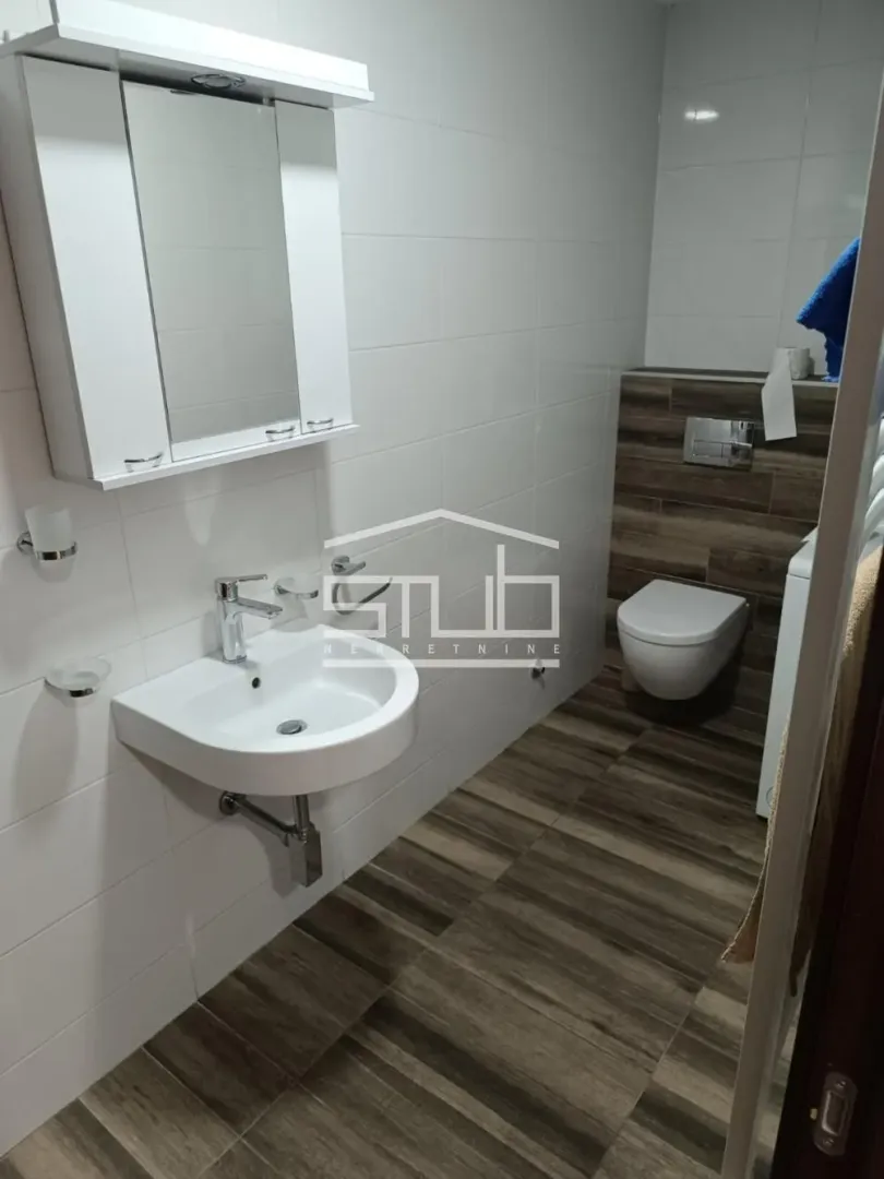 Moderno kupatilo sa umivaonikom, ogledalom i WC šoljom.
