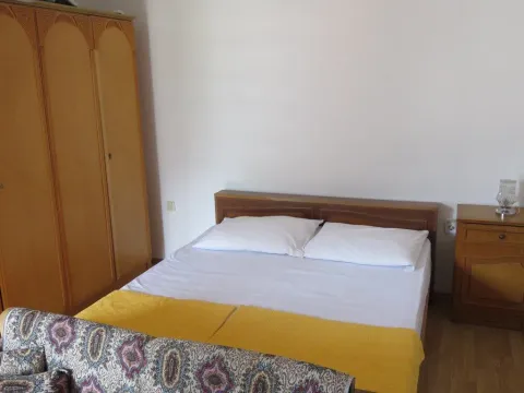 Jednostavno namještena spavaća soba sa bračnim krevetom i drvenim ormarom. - image 2