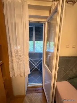 View through the balcony door onto a small outdoor balcony with a clothes drying rack. - image 7