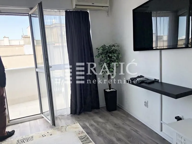 Living room with access to the terrace and a wall-mounted TV.