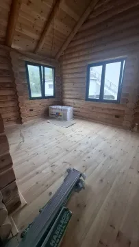 A view of an empty room in a wooden house under construction with wooden floors and walls. - image 16