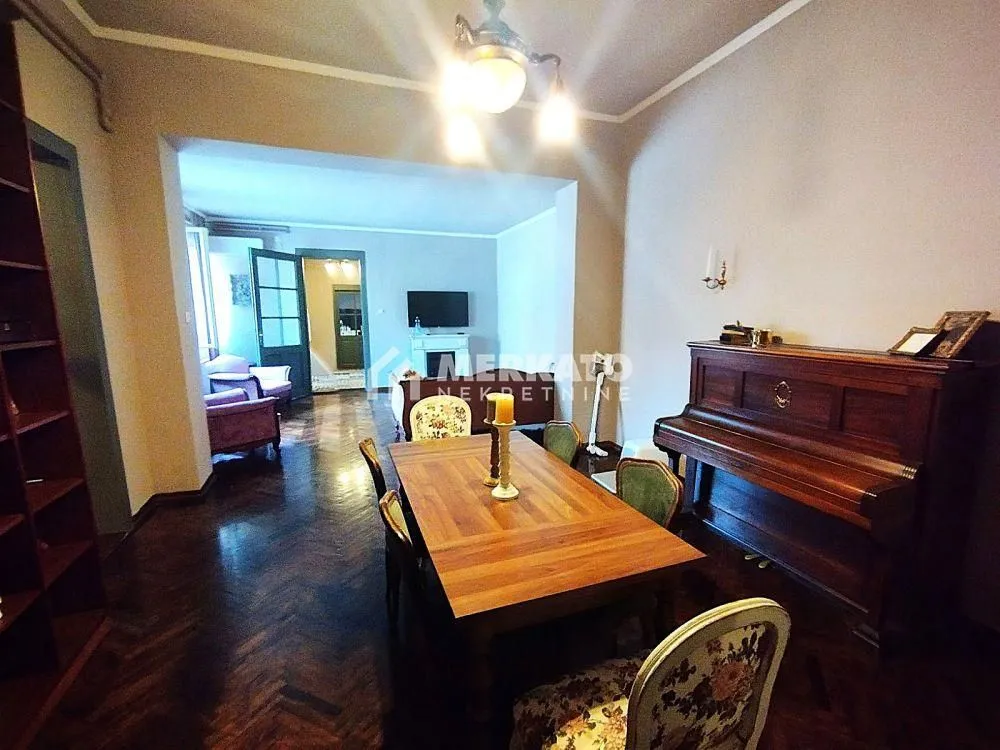Prostrana dnevna soba sa trpezarijskim stolom i klavirom.