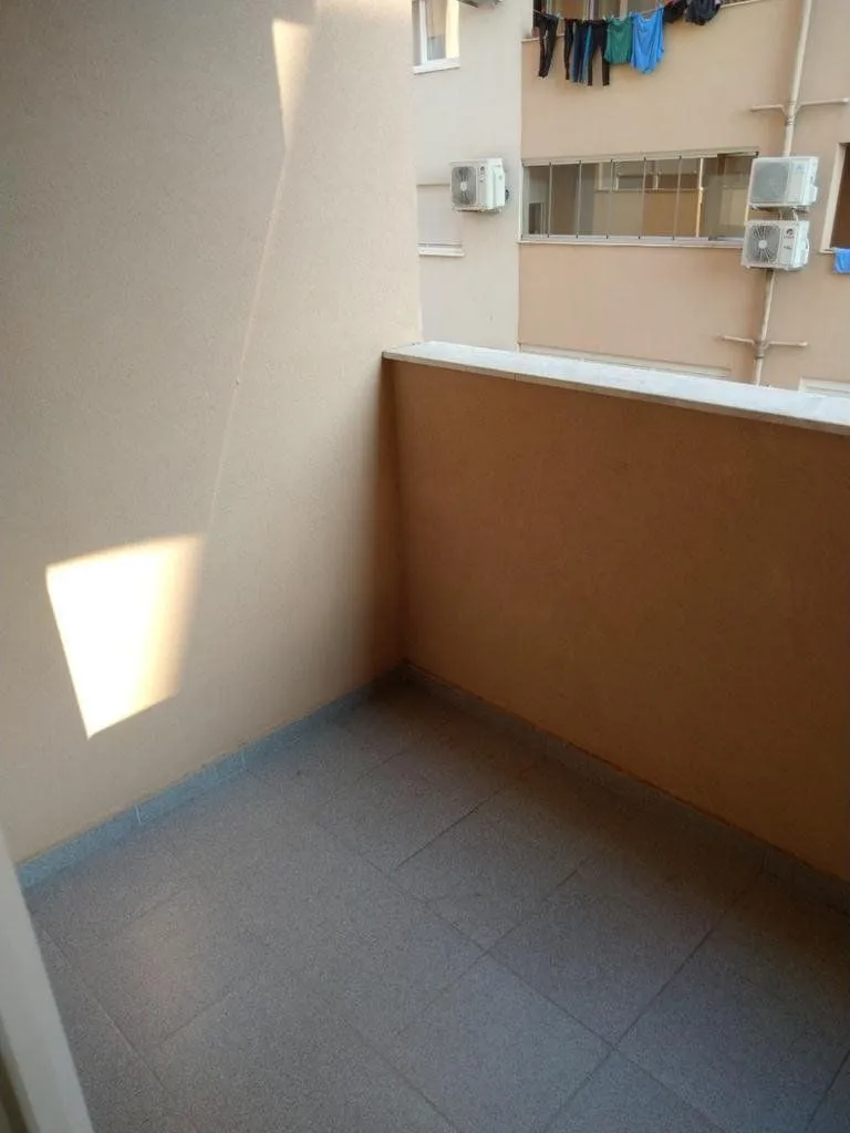 Smaller enclosed balcony with tiled flooring and a view of the neighboring building.