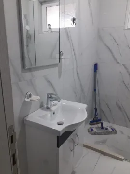 Kupatilo sa bijelim lavaboom, ogledalom i pločicama sa dezenom mermera. - image 10