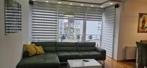Dnevna soba sa zelenom ugaonnom garniturom i velikim prozorom. - image 6
