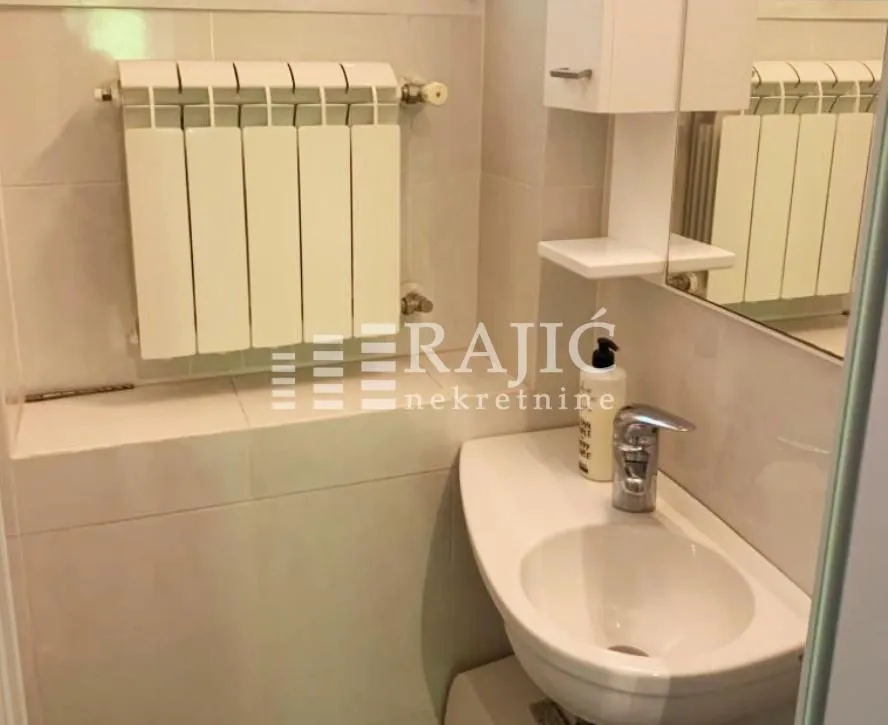 Small bathroom with a sink, mirror, and radiator.