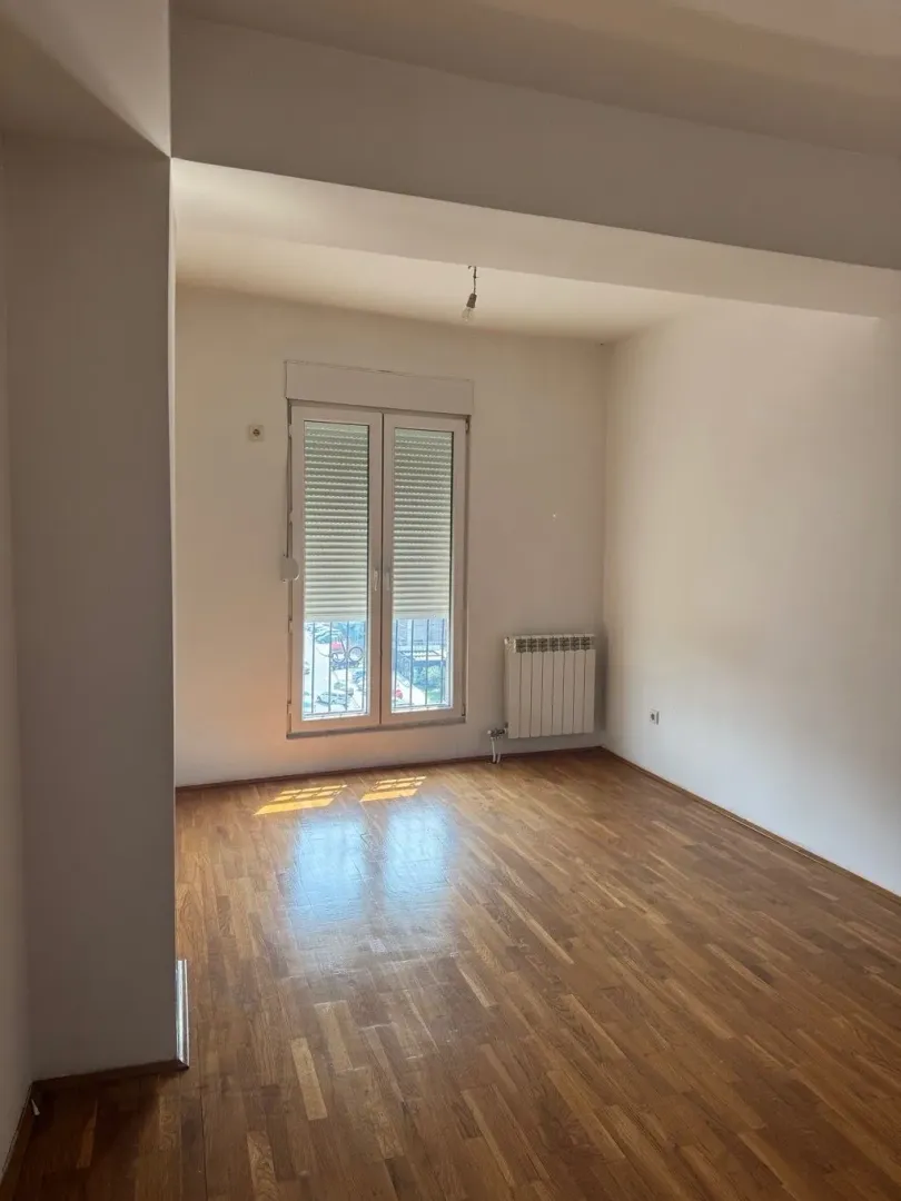 Empty room with parquet flooring and balcony doors.