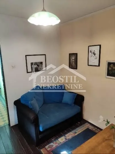 Small living room with a blue armchair and pictures on the wall.