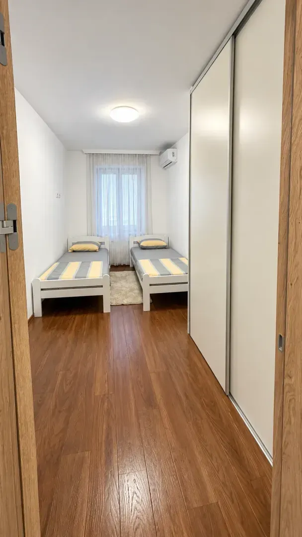 Spavaća soba sa dva odvojena kreveta i velikim ugradnim ormarom.