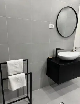 Moderno opremljeno kupatilo sa umivaonikom, crnim elementima i okruglim ogledalom. - image 10