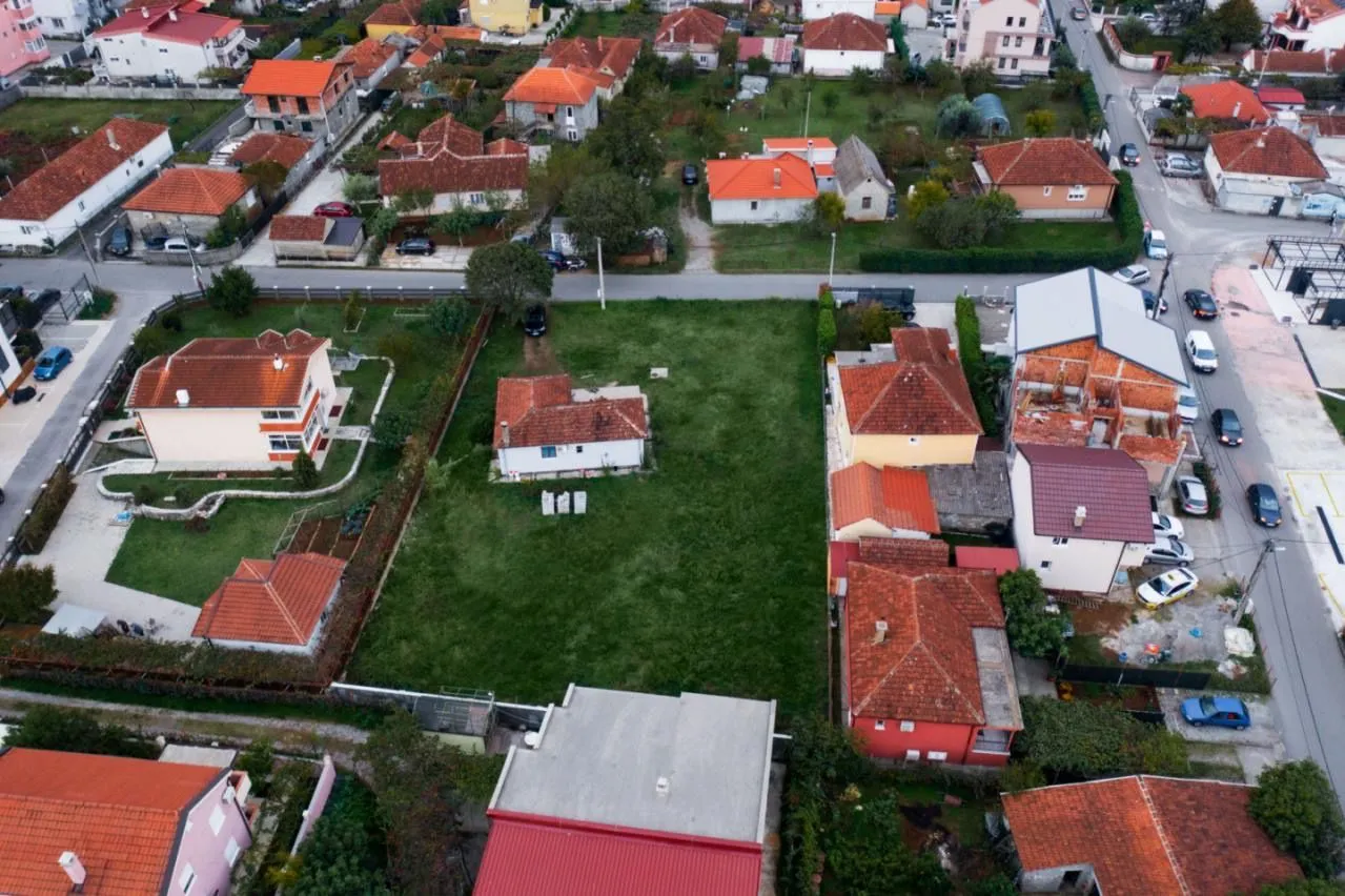 Pogled iz vazduha na plac sa kućom i okolno naselje.