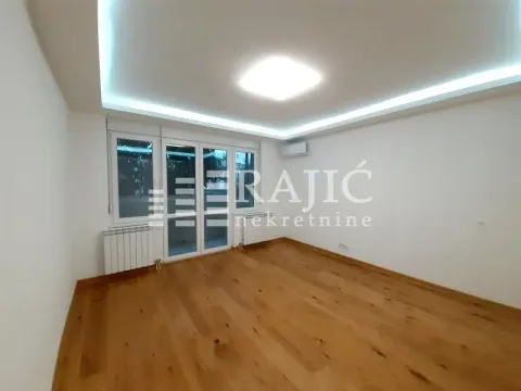 Prazna dnevna soba sa drvenim podom i spuštenim plafonom sa rasvetom. - image 3