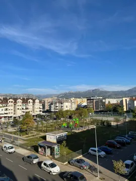 Pogled sa terase na gradski park i okolne zgrade sa planinama u pozadini. - image 13
