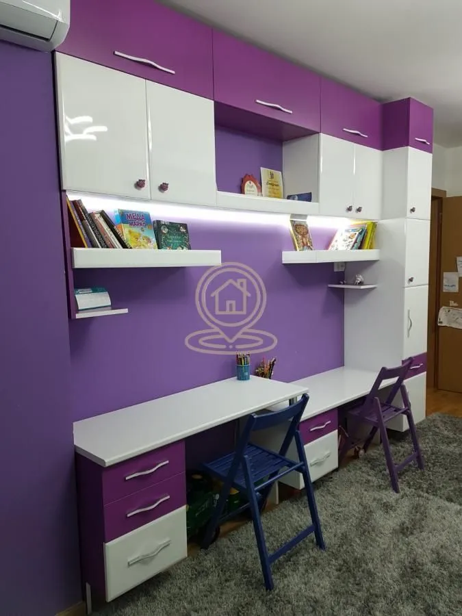 Children's room with a desk and purple and white furniture.