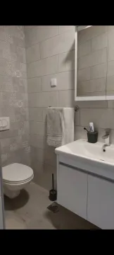 Modern bathroom with a washbasin, toilet, and a mirror cabinet. - image 4