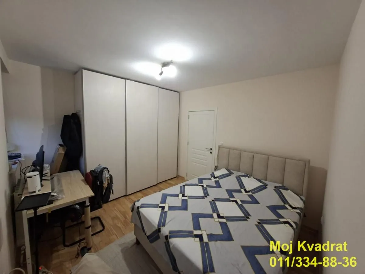 Nameštena spavaća soba sa bračnim krevetom, velikim garderoberom i radnim stolom.