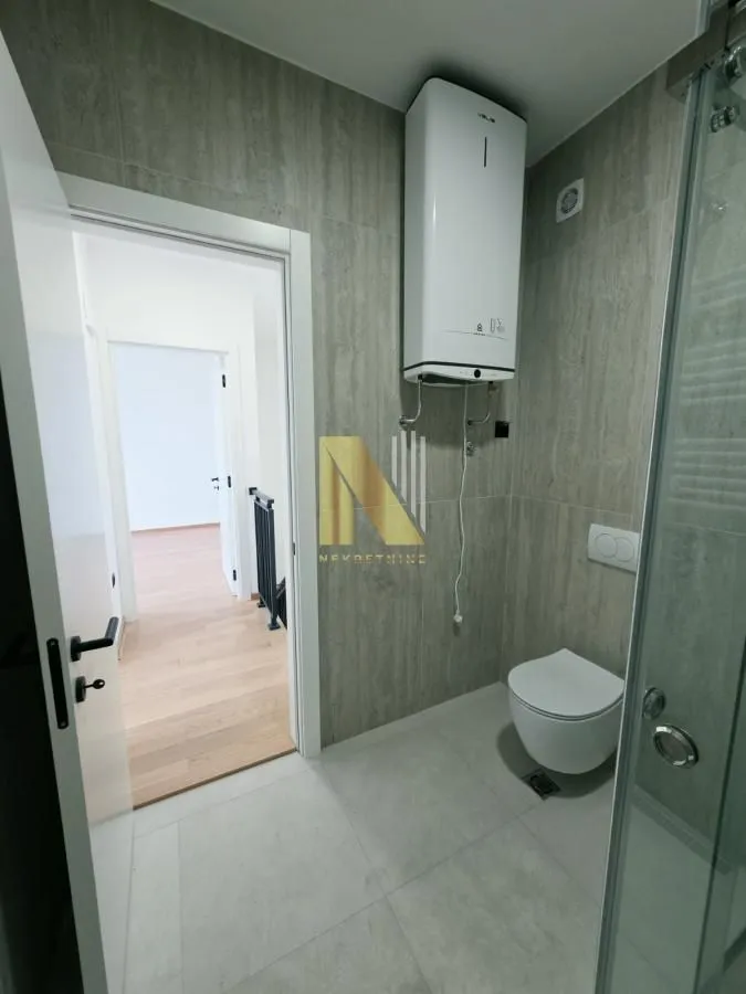 Moderno kupatilo sa WC šoljom, bojlerom i tuš kabinom.
