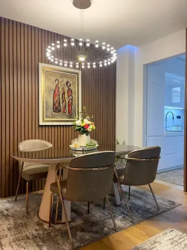Trpezarija sa modernim stolom, stolicama i ukrasnim drvenim panelom na zidu. - image 4
