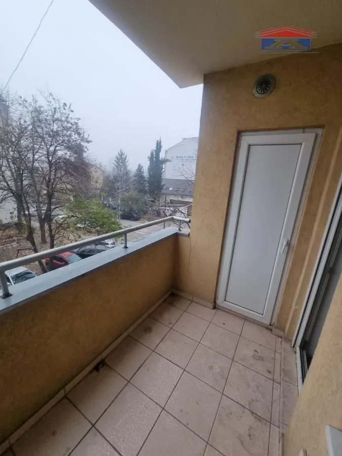 Manji natkriveni balkon sa keramičkim pločicama i pogledom na ulicu.