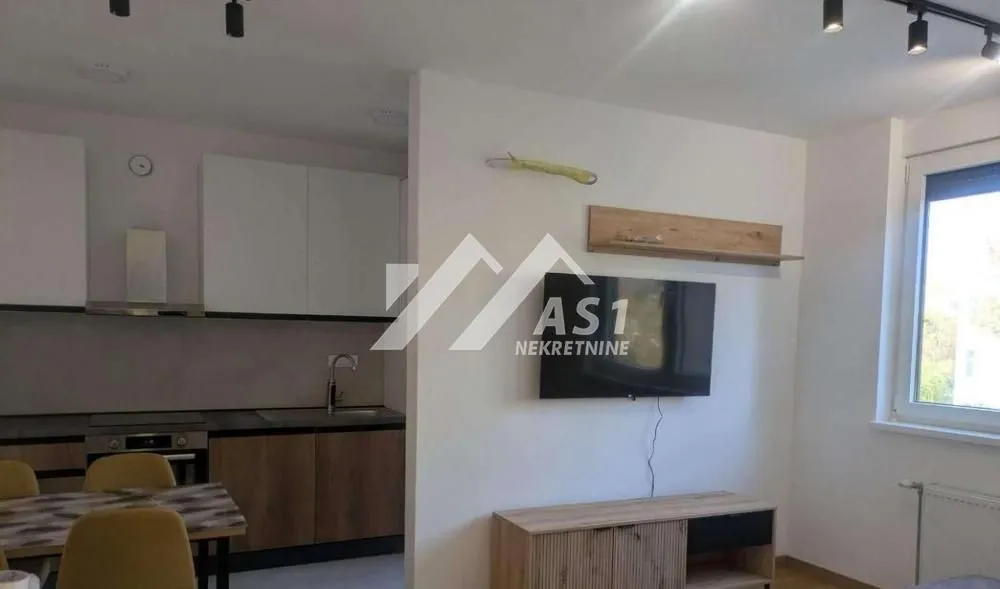 Living room with a TV and a dining area in the background.