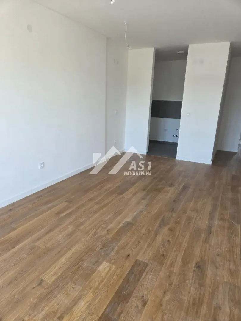 Empty living room with wood flooring and white walls.