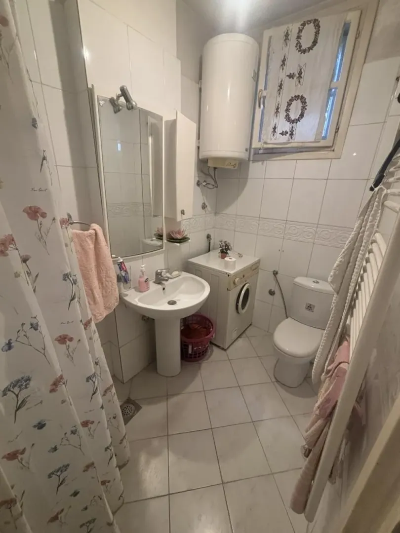 Small bathroom equipped with a washbasin, toilet, shower, and washing machine.