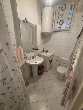 Small bathroom equipped with a washbasin, toilet, shower, and washing machine. - image 3