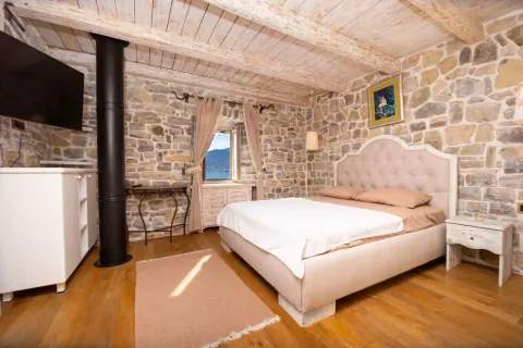 Furnished bedroom with stone walls and a wooden ceiling. - image 14