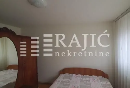 Furnished bedroom with a double bed and a wooden wardrobe.