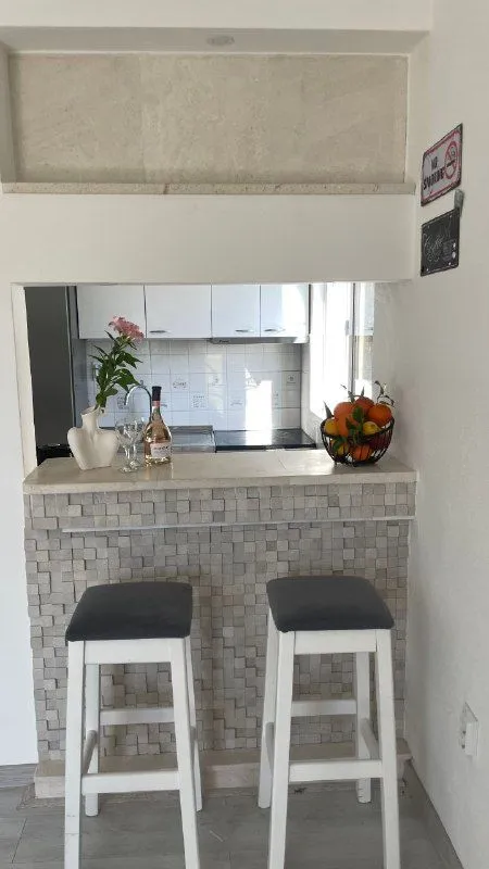 Šank sa barskim stolicama i pogledom na kuhinju.