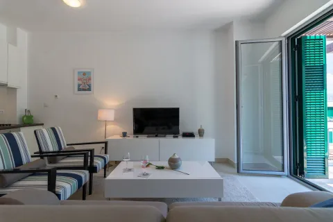 Svijetla dnevna soba sa foteljama, televizorom i otvorenim vratima prema balkonu. - image 13