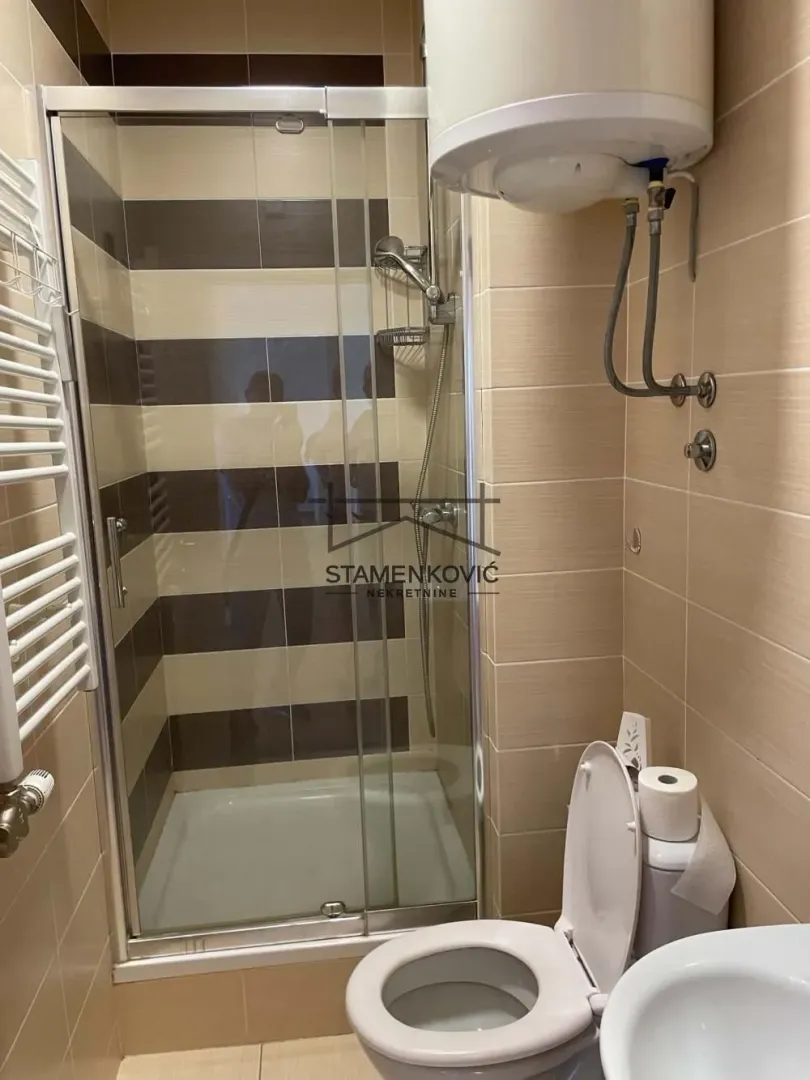 Manje kupatilo sa tuš kabinom, WC šoljom i bojlerom.