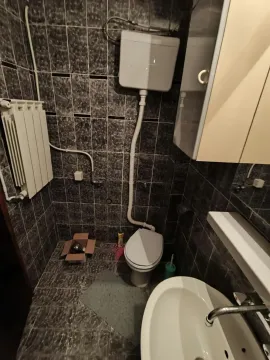 Manje kupatilo sa tamnim pločicama, wc šoljom, umivaonikom i radijatorom. - image 16