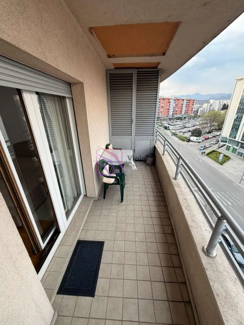 Furnished balcony with seating set and street view.