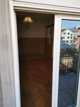 Pogled kroz otvorena balkonska vrata na praznu prostoriju sa parketom. - image 2