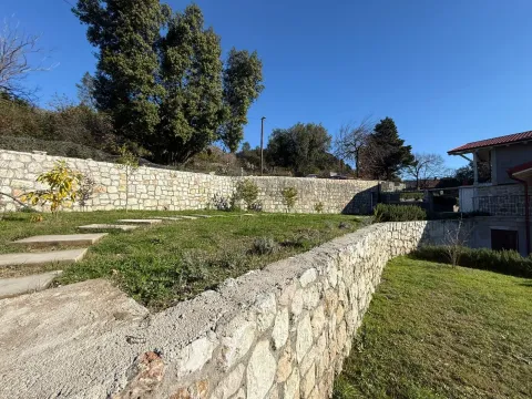 Dvorište kuće sa kamenim zidovima i uređenom travnatom površinom. - image 4