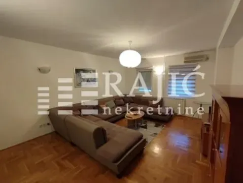 Spacious living room with a sectional sofa and wooden parquet flooring. - image 4
