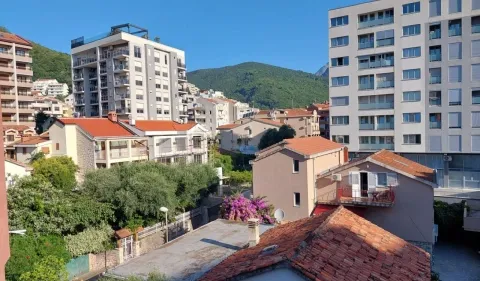 Pogled sa prozora na okolne zgrade i zeleno brdo u pozadini. - image 4