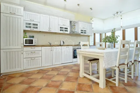 Spacious kitchen with white cabinetry and a dining table. - image 10
