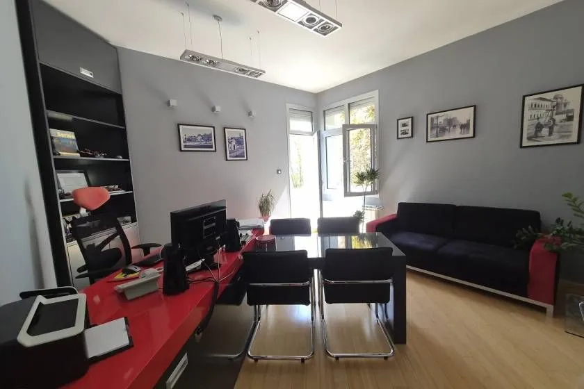 Living room furnished as an office with a desk, sofa, and shelving units.